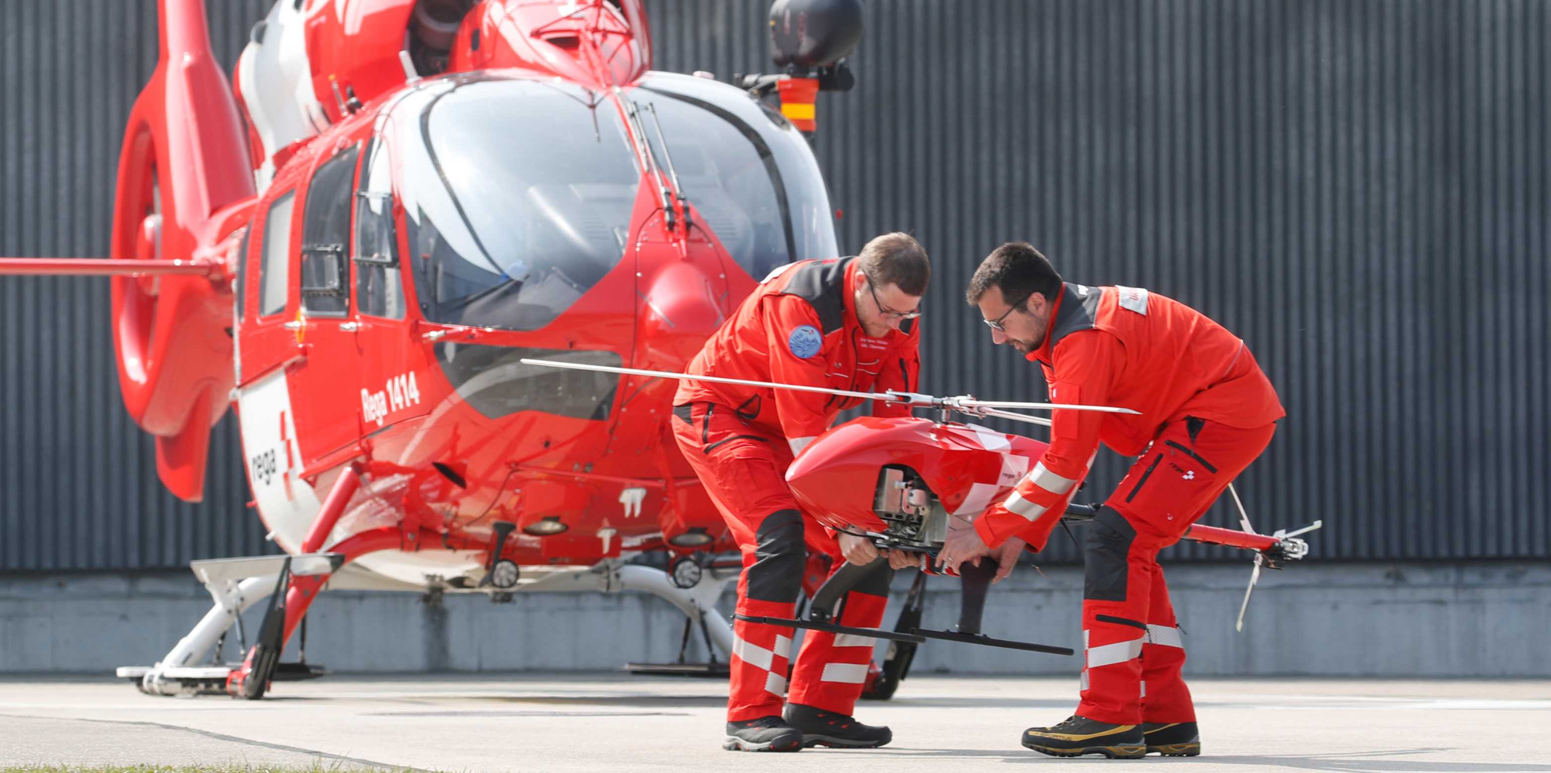 Drone operator Corti of Swiss air rescue company Rega and Maeder of Oblivion Aerial company place the new Rega-Drone in front of a rescue helicopter in Duebendorf.